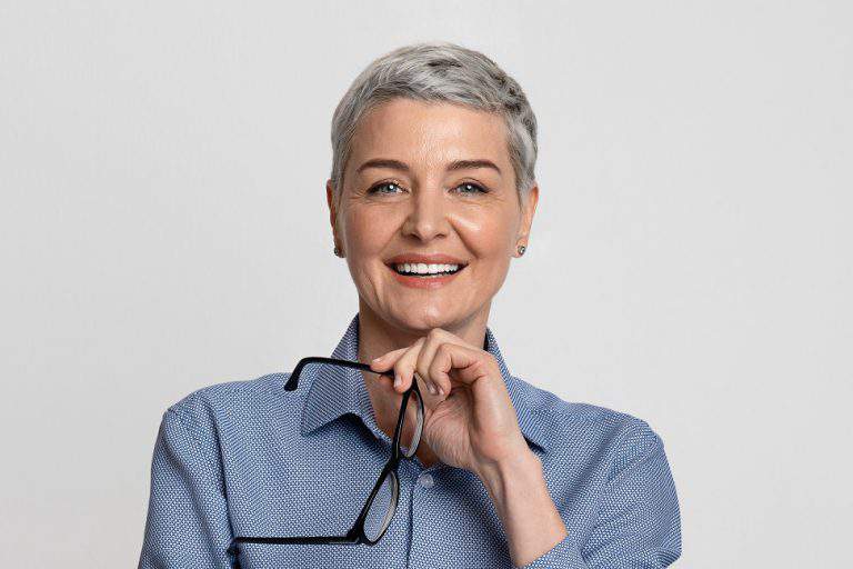 Portrait Of Beautiful Mature Businesswoman Holding Glasses And Smiling At Camera