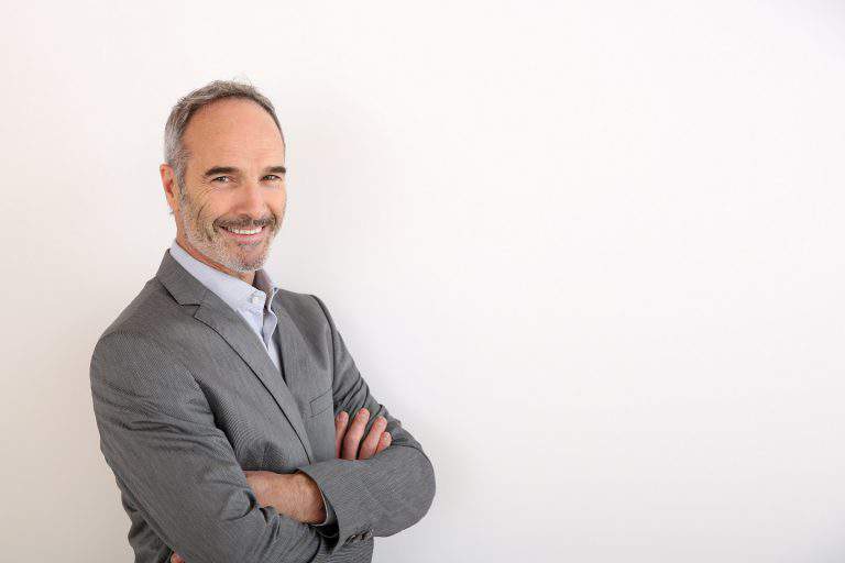 Cheerful senior businessman standing on white background