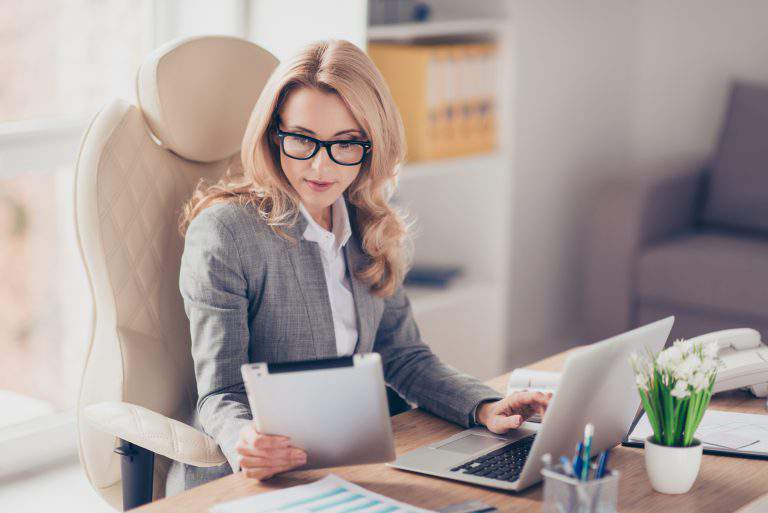 Pretty, charming, blonde woman using, browsing, typing, searching, expertising, working online on computer and tablet in workplace, using wi-fi internet